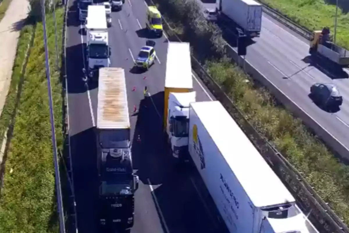 Una carretera amb trànsit detingut a causa d?un accident on s?observen camions i vehicles d?emergència.