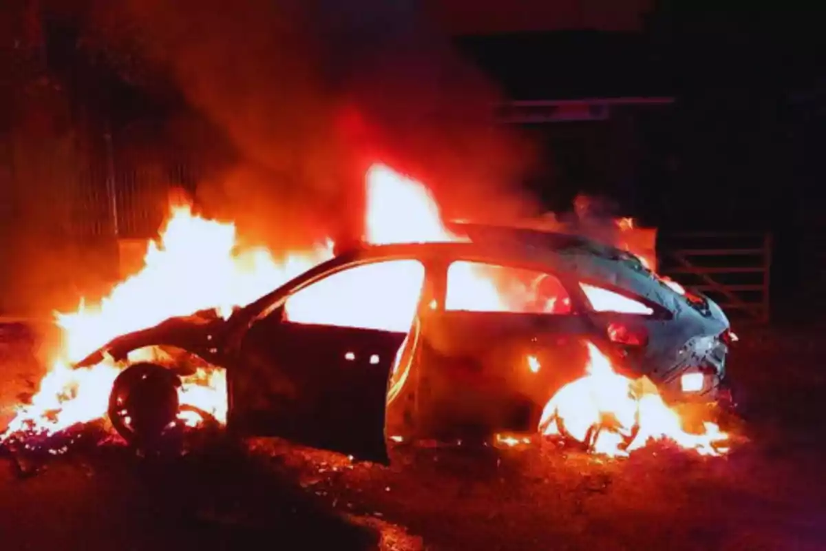 Un coche en llamas en la oscuridad de la noche.