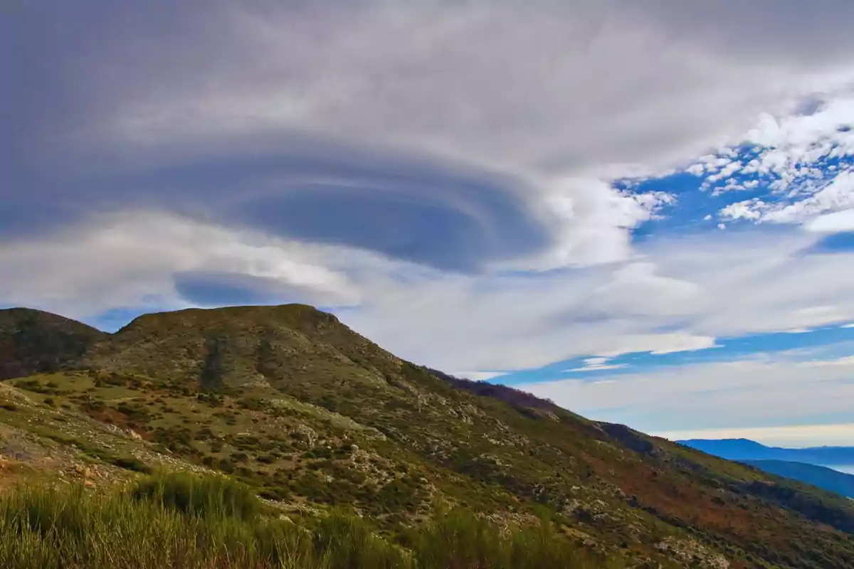 Paisaje montañoso con nubes lenticulares en el cielo.