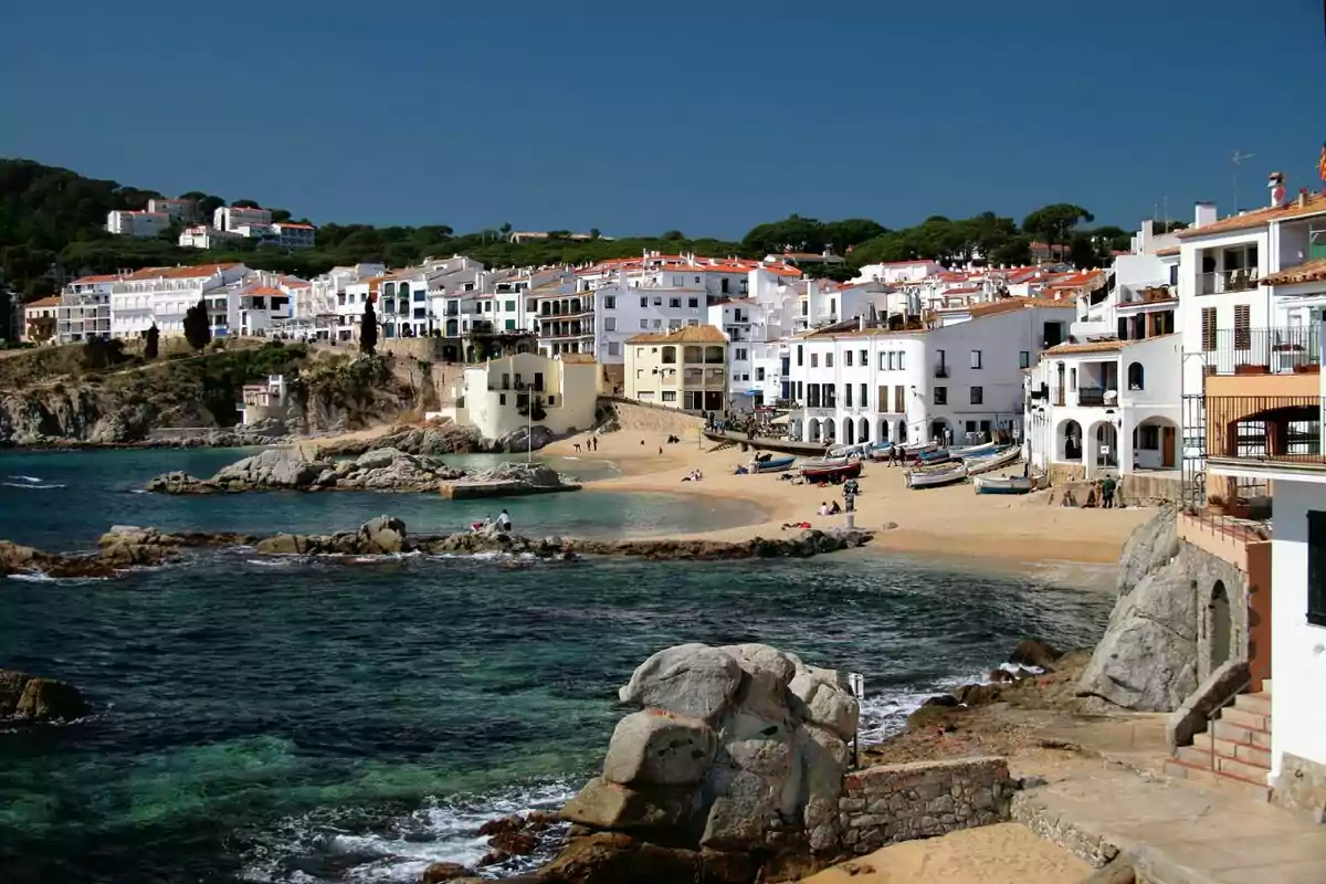 Vista d'un pintoresc poble costaner amb cases blanques, una platja de sorra i pots a la riba. Vista d'un pintoresc poble costaner amb cases blanques, una platja de sorra i pots a la riba.