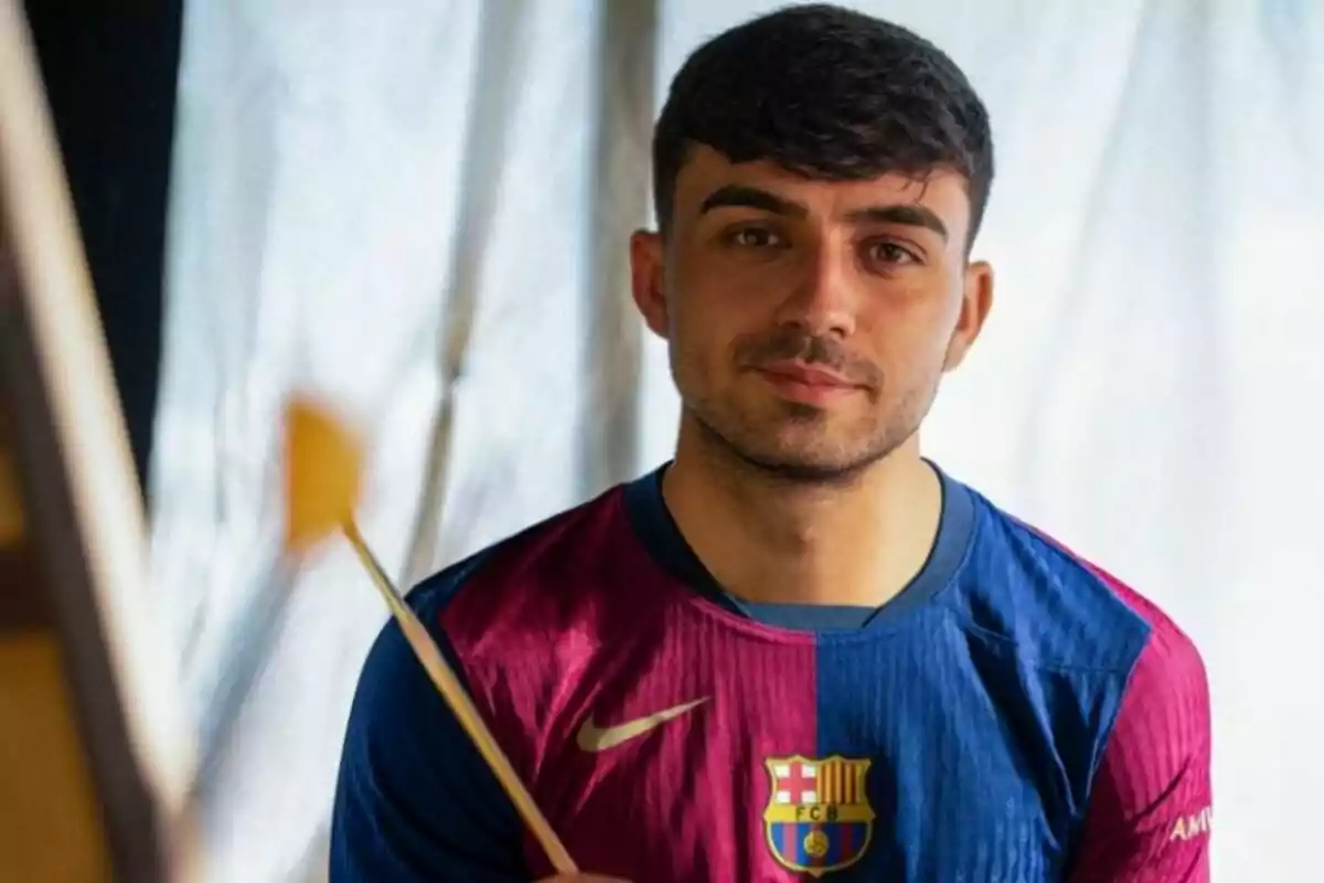 Un hombre con una camiseta del FC Barcelona sosteniendo un pincel.