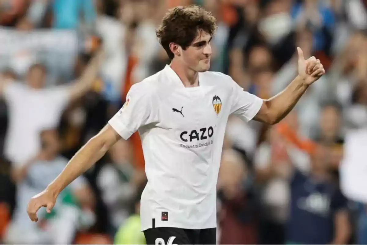 Un jugador de futbol amb la samarreta del València CF celebra al camp amb el polze cap amunt. Un jugador de futbol amb la samarreta del València CF celebra al camp amb el polze cap amunt.