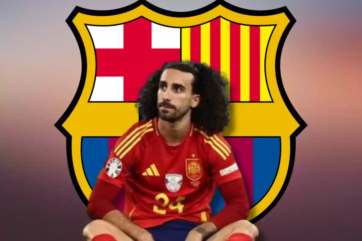 Un jugador de fútbol con el uniforme de la selección española está sentado frente al escudo del FC Barcelona.