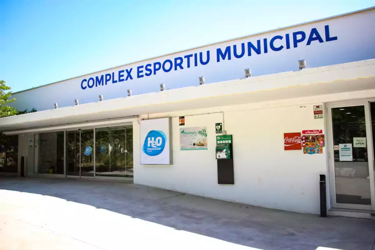 Entrada d'un complex esportiu municipal amb rètol de "Complex Esportiu Municipal" i logotip de H2O Fitness Club.