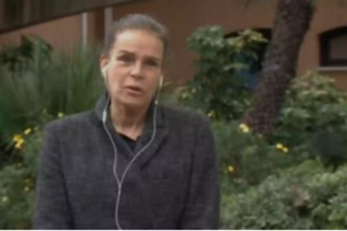 Una persona con auriculares está de pie frente a un fondo de vegetación.