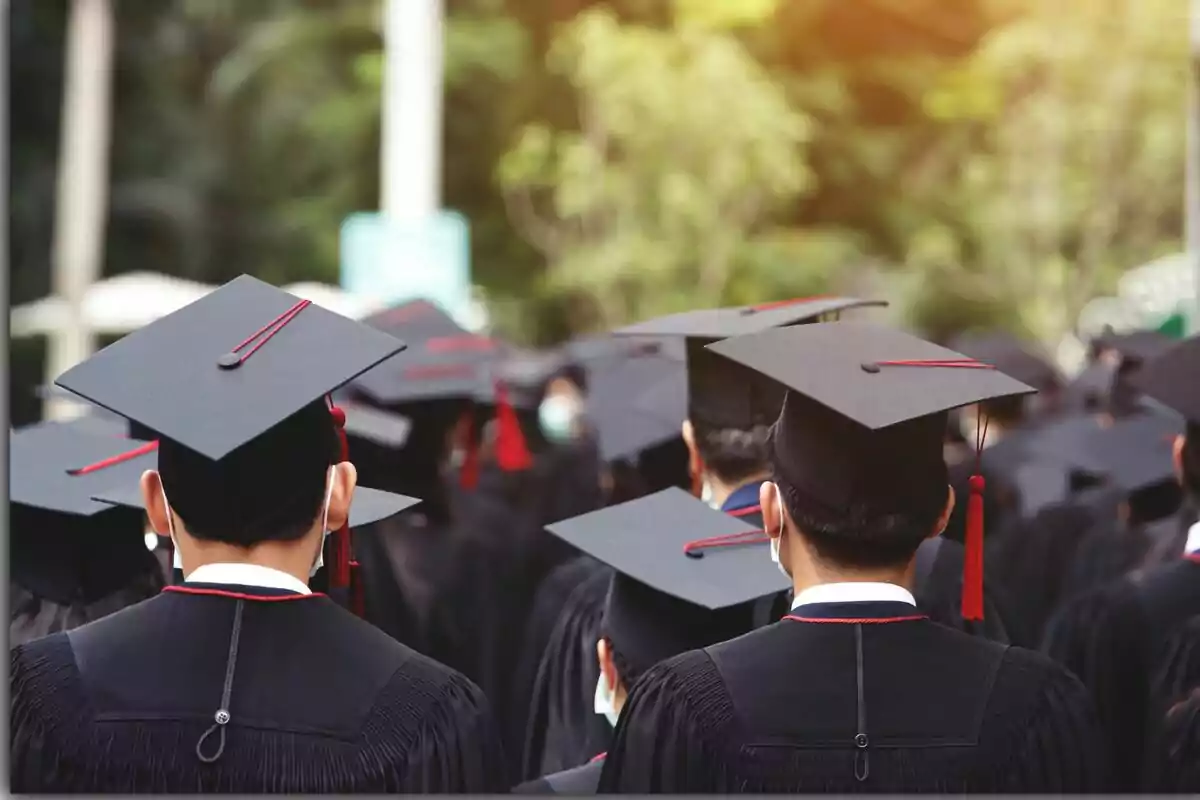 Grup d’estudiants amb toga i birret en una cerimònia de graduació a l’aire lliure Grup d’estudiants amb toga i birret en una cerimònia de graduació a l’aire lliure