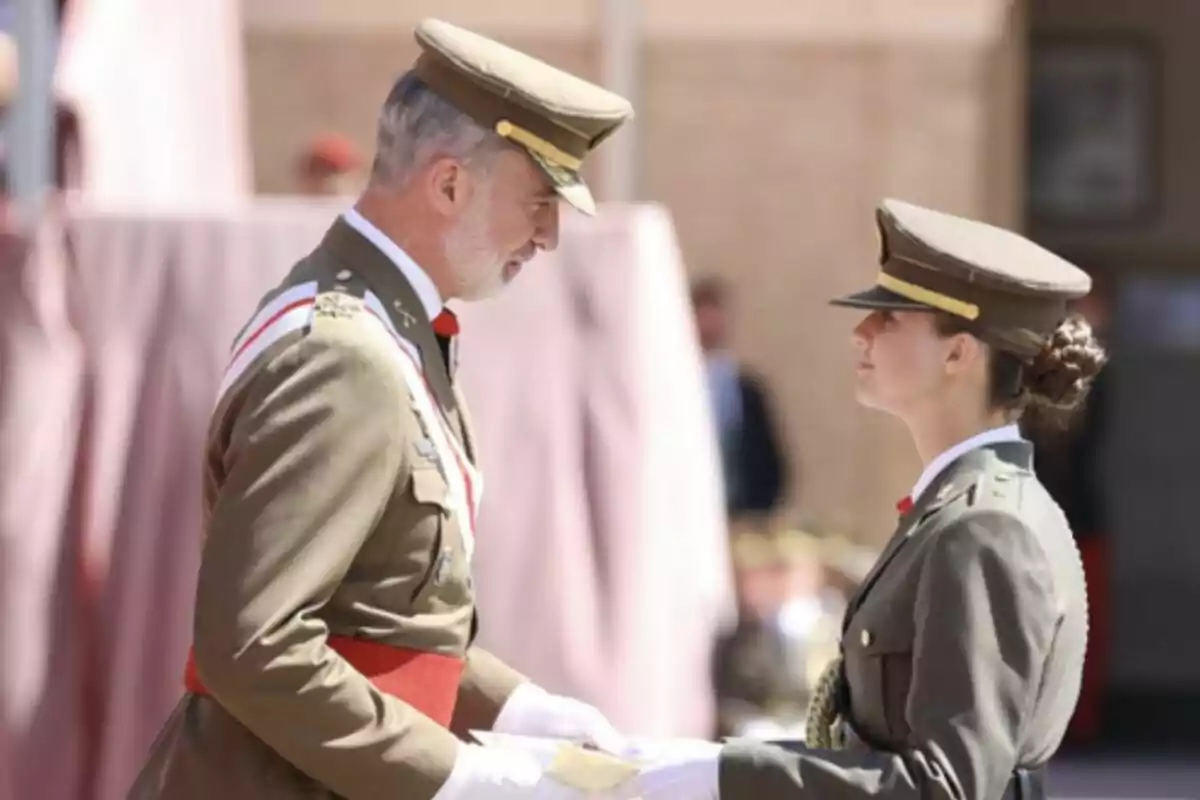 Dos personas en uniforme militar se miran mientras una de ellas entrega un documento a la otra.