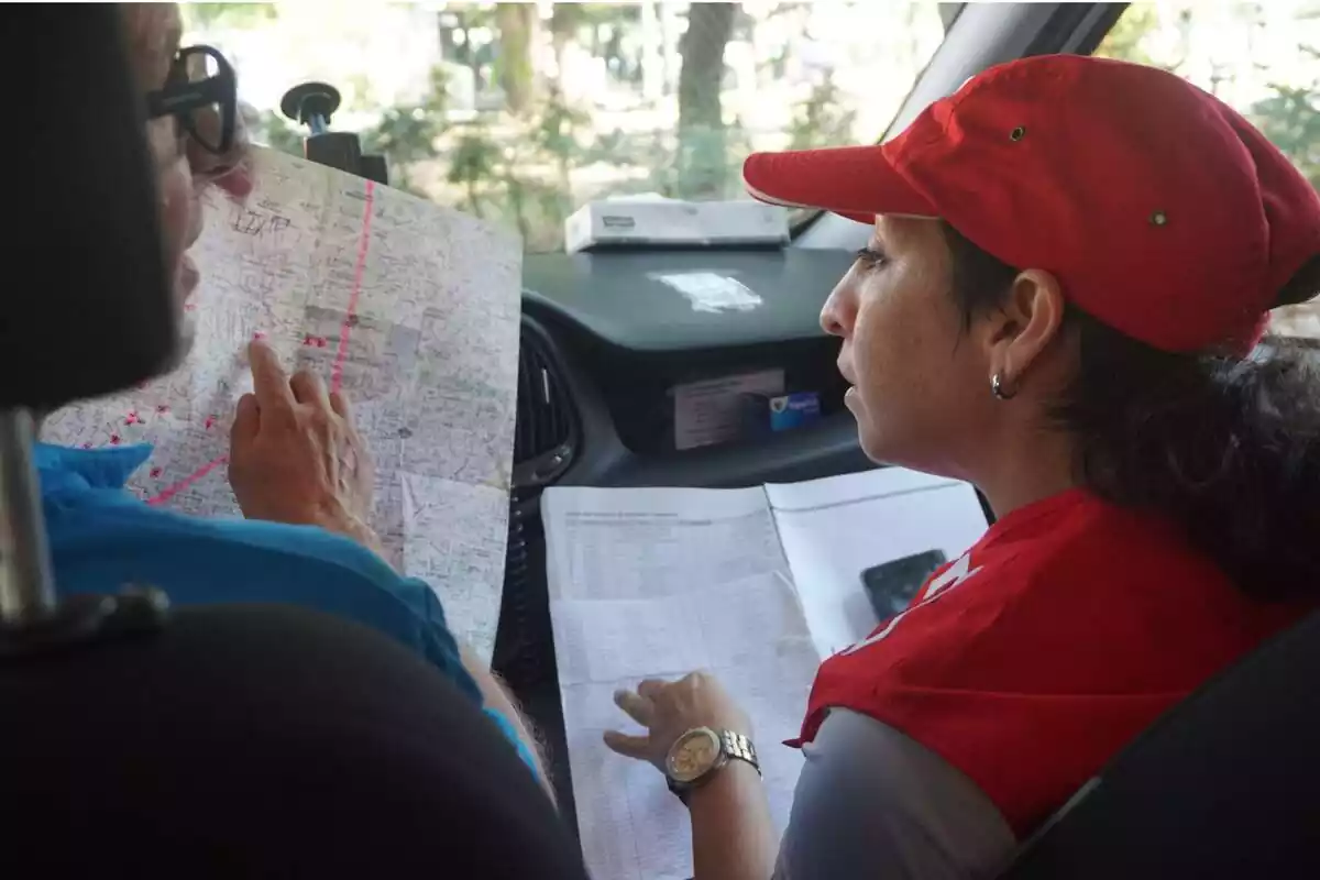 Dues voluntàries de Creu Roja amb uns mapes a la mà