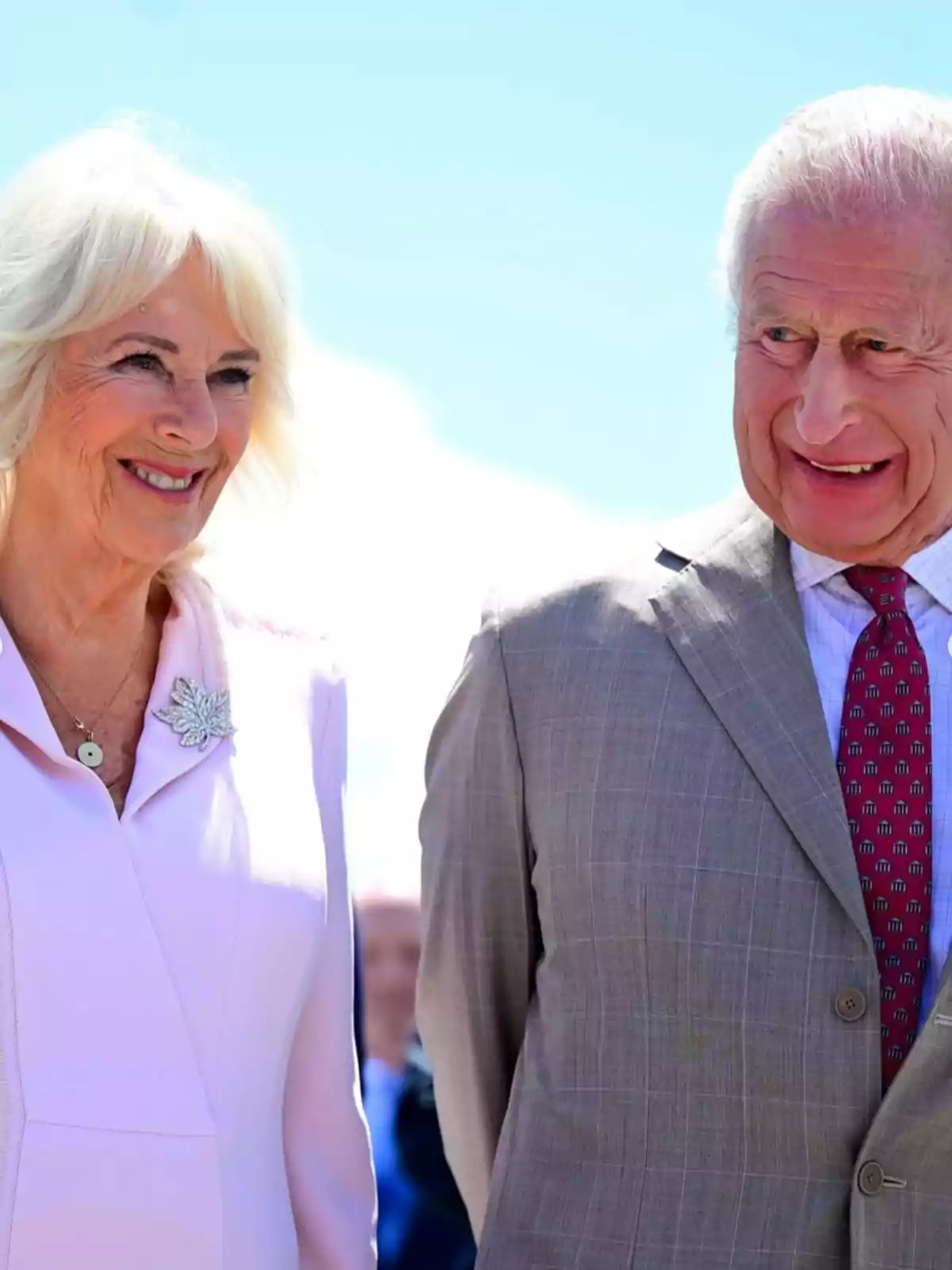 El rei Carles III i la reina consort Camila somriuen mentre està dreta a l’aire lliure sota un cel blau. El rei Carles III i la reina consort Camila somriuen mentre està dreta a l’aire lliure sota un cel blau.