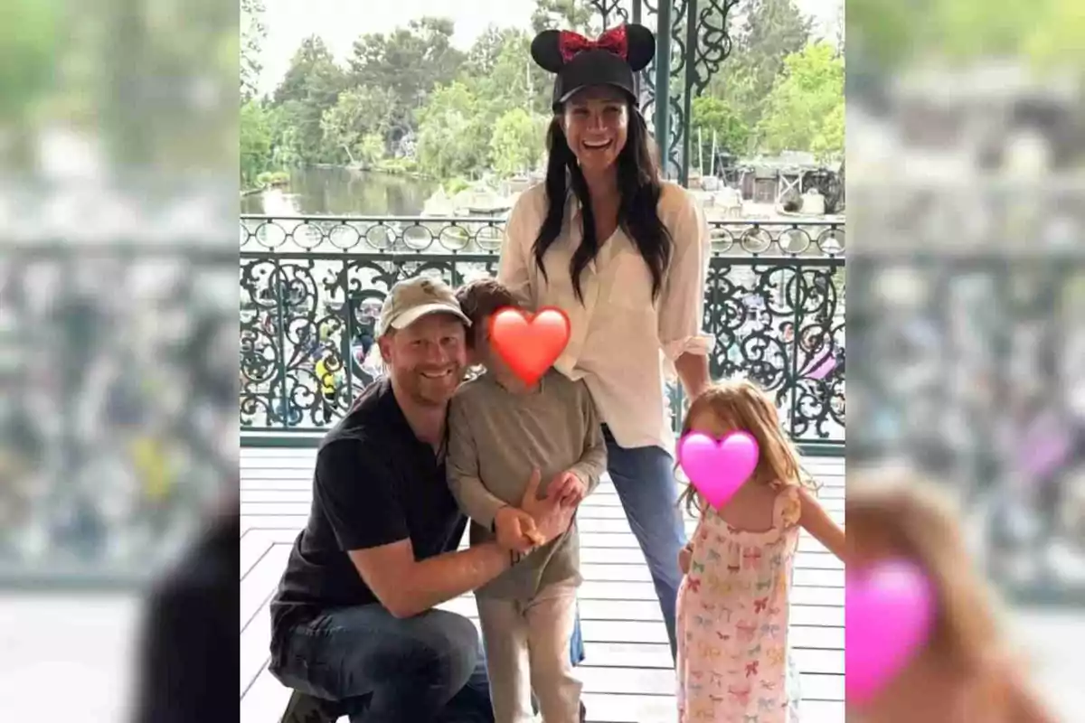 Meghan Markle and Prince Harry's family poses at a Disney's theme park, Meghan is wearing a cap with mouse ears, and the children's faces are covered with colorful hearts. Meghan Markle and Prince Harry's family poses at a Disney's theme park, Meghan is wearing a cap with mouse ears, and the children's faces are covered with colorful hearts.
