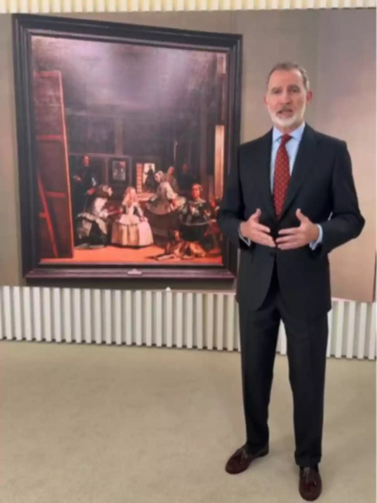 King Felipe VI in a dark suit and red tie posing in front of Velázquez’s painting Las Meninas King Felipe VI in a dark suit and red tie posing in front of Velázquez’s painting Las Meninas