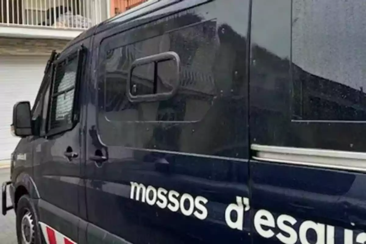 Una furgoneta de los Mossos d'Esquadra estacionada en una calle frente a un edificio.