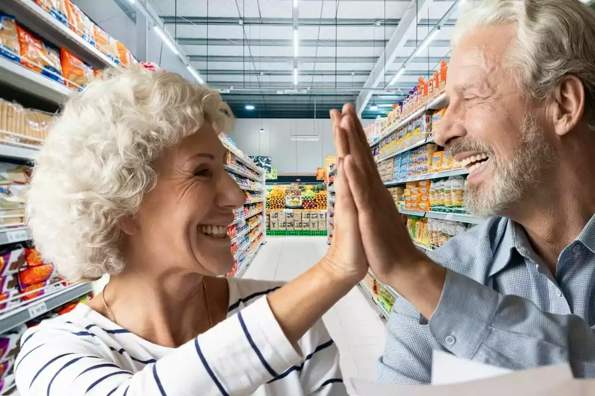 Dues persones grans somrient i xocant les mans en un passadís de supermercat.