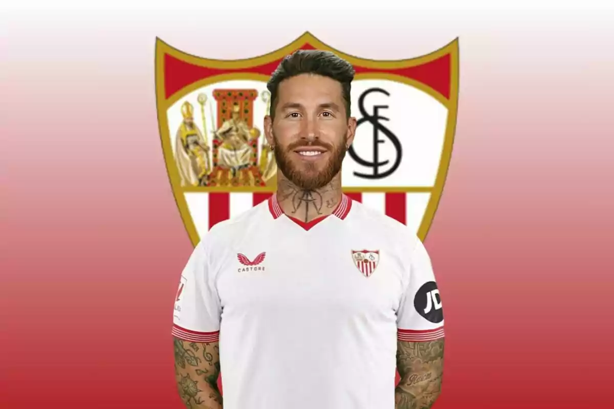 Jugador de futbol amb la samarreta del Sevilla FC posant davant de l'escut de l'equip.