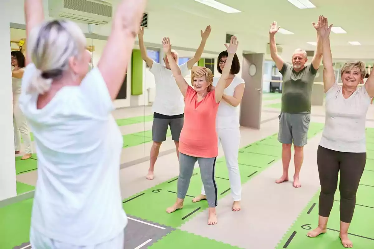 Gent gran fent exercicis d'estirament en una classe grupal en un gimnàs.