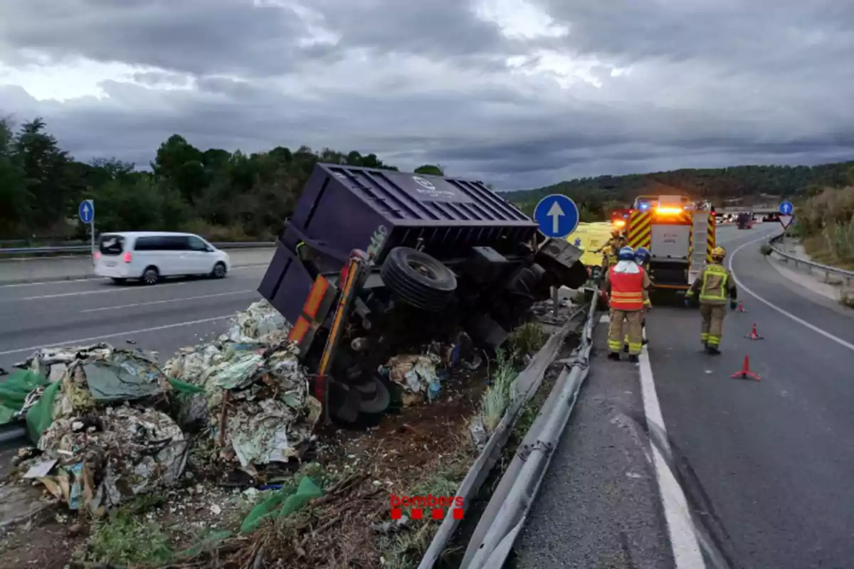 Un camió bolcat a la carretera amb runes escampades i personal d'emergència treballant al lloc.