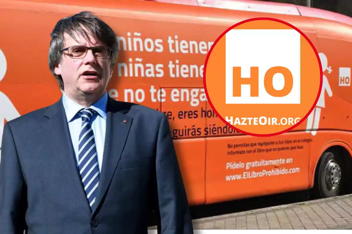 Un home amb vestit i corbata està dret davant d'un autobús taronja amb el logotip de HazteOir.org i un missatge en espanyol sobre nens i nenes.