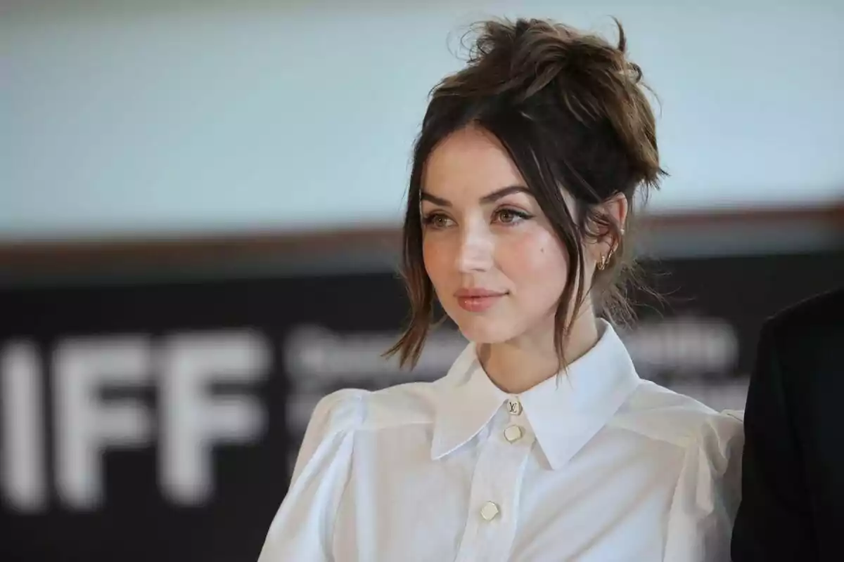 Una persona con cabello recogido y camisa blanca en un evento. Una persona con cabello recogido y camisa blanca en un evento.