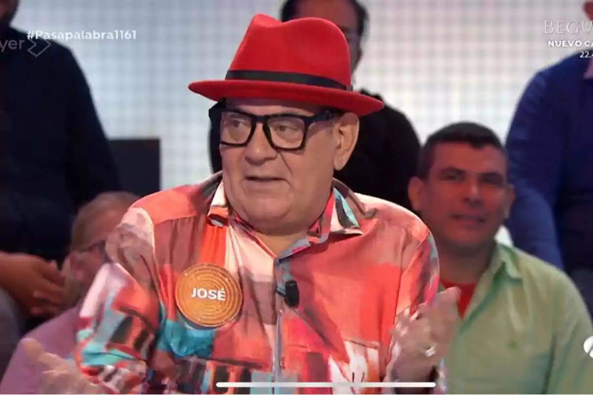 Un home amb barret vermell i camisa acolorida participa a un programa de televisió. Un home amb barret vermell i camisa acolorida participa a un programa de televisió.