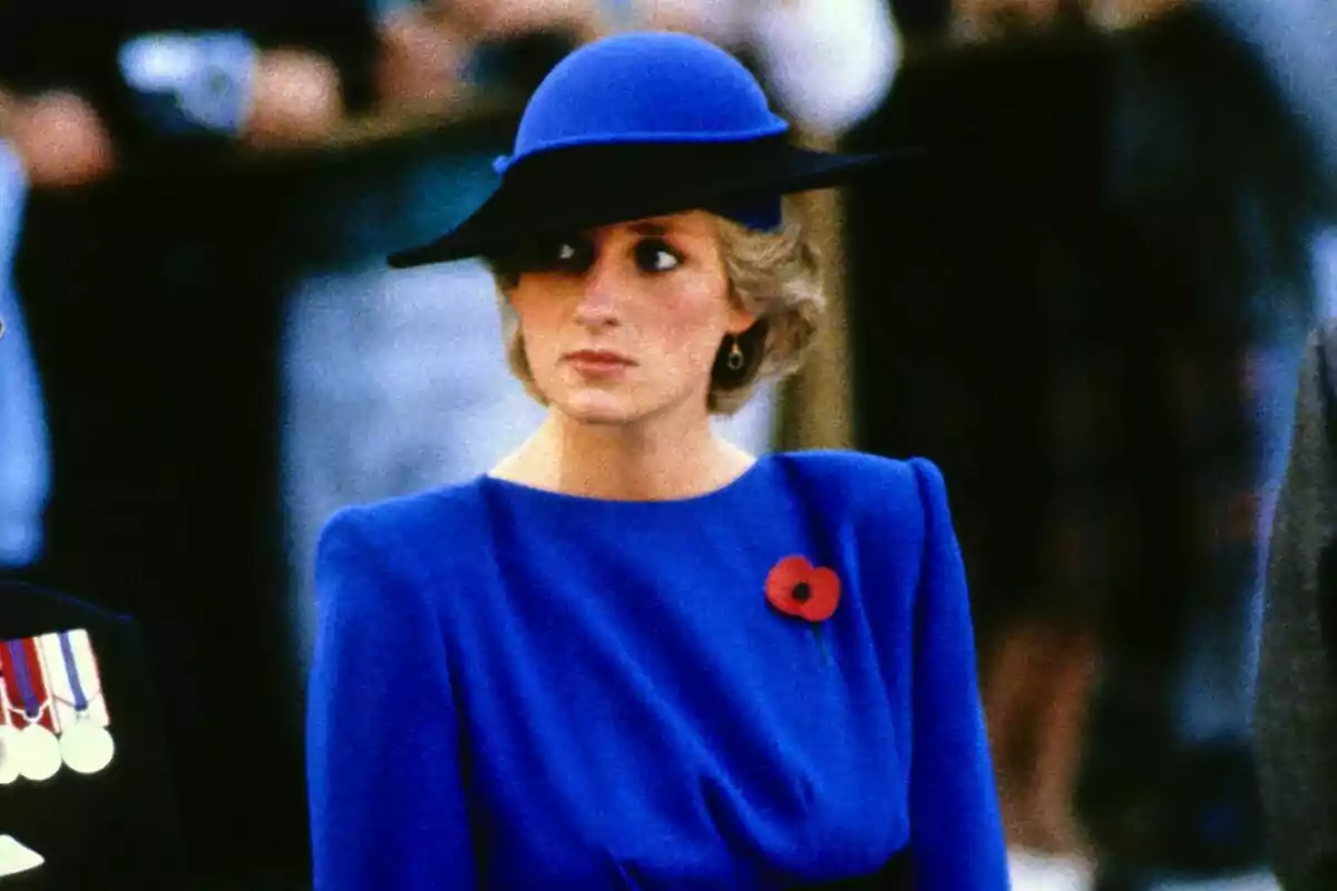 Una persona amb un elegant barret blau i vestit a joc porta un fermall de rosella vermella. Una persona amb un elegant barret blau i vestit a joc porta un fermall de rosella vermella.