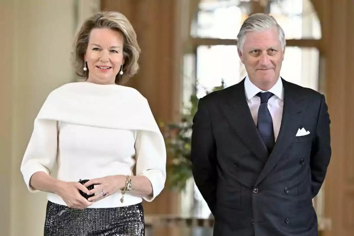 Dos personas elegantemente vestidas posan en un entorno interior. Dos personas elegantemente vestidas posan en un entorno interior.