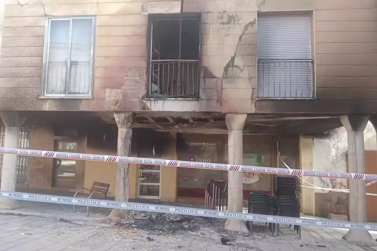 Edificio con fachada quemada y cinta de policía que indica no pasar.