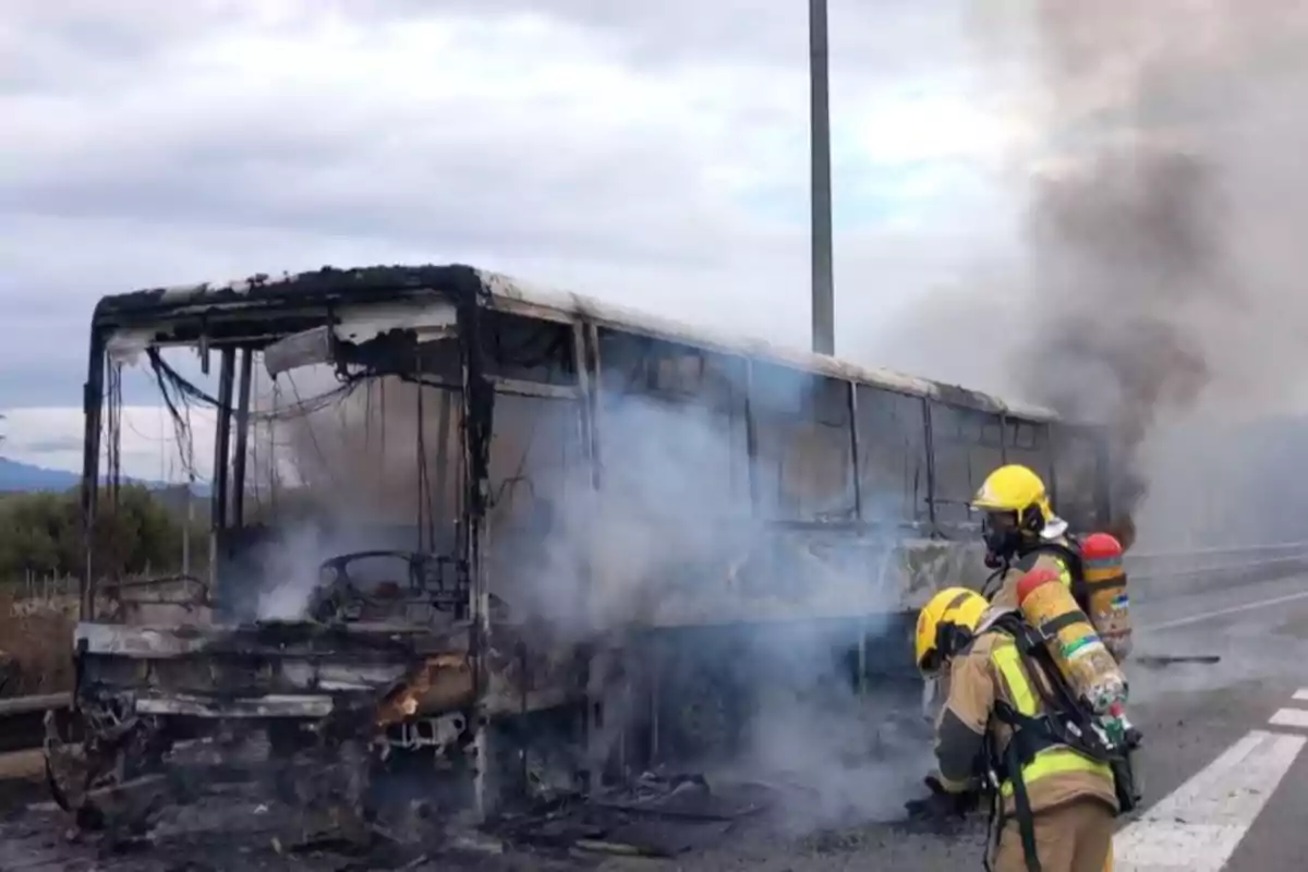 Bomberos apagando un autobús incendiado