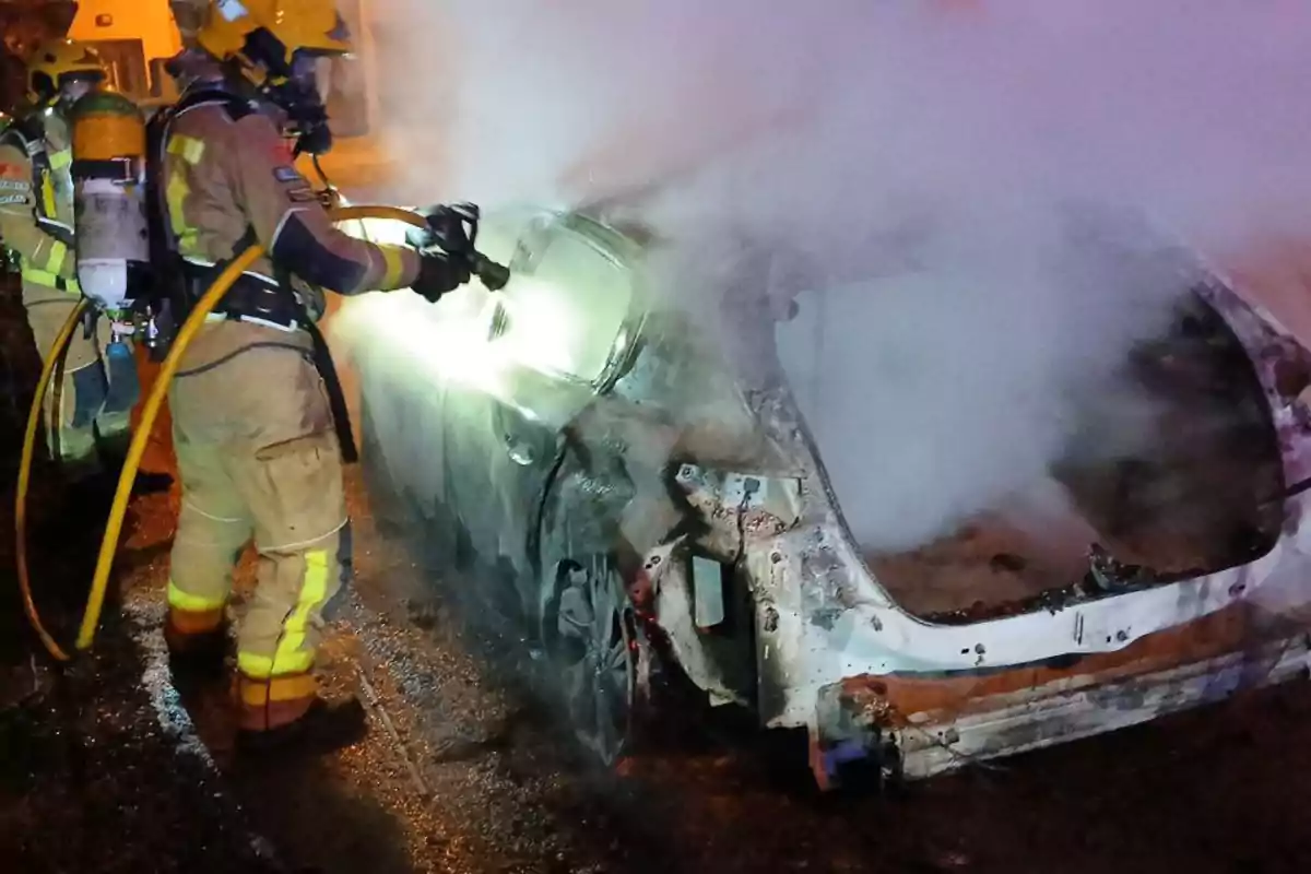 Bombers apagant un incendi en un automòbil a la nit