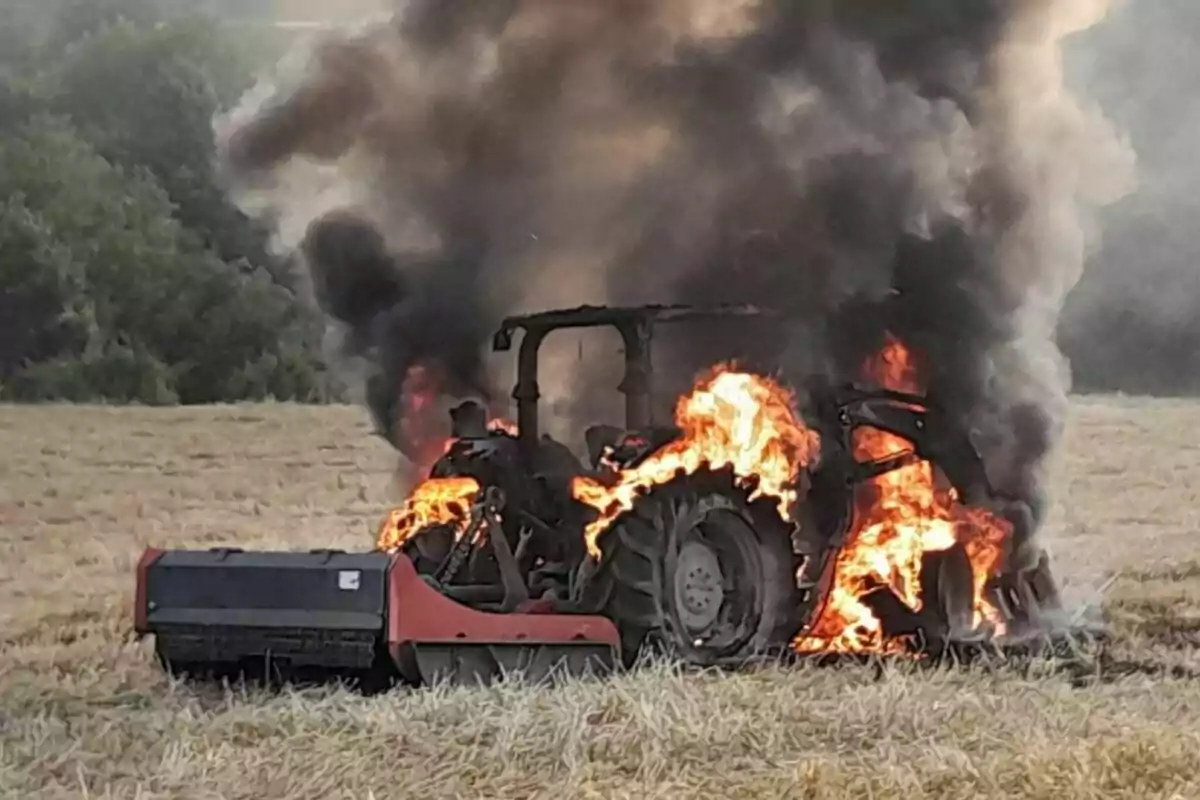 Tractor envoltat en flames al mig d’un camp amb fum negre que s’eleva cap al cel