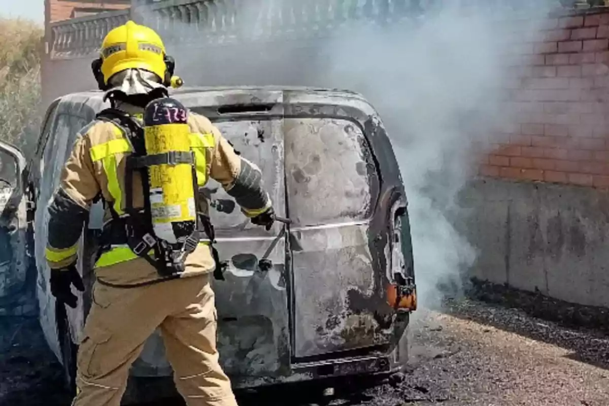 Bombero apagando un incendio en una camioneta quemada mientras sale humo