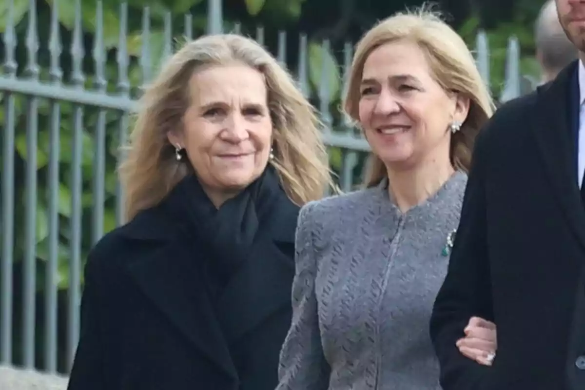 La infanta Elena somrient amb un abric i bufanda negres al costat de la infanta Cristina somrient en abric gris La infanta Elena somrient amb un abric i bufanda negres al costat de la infanta Cristina somrient en abric gris