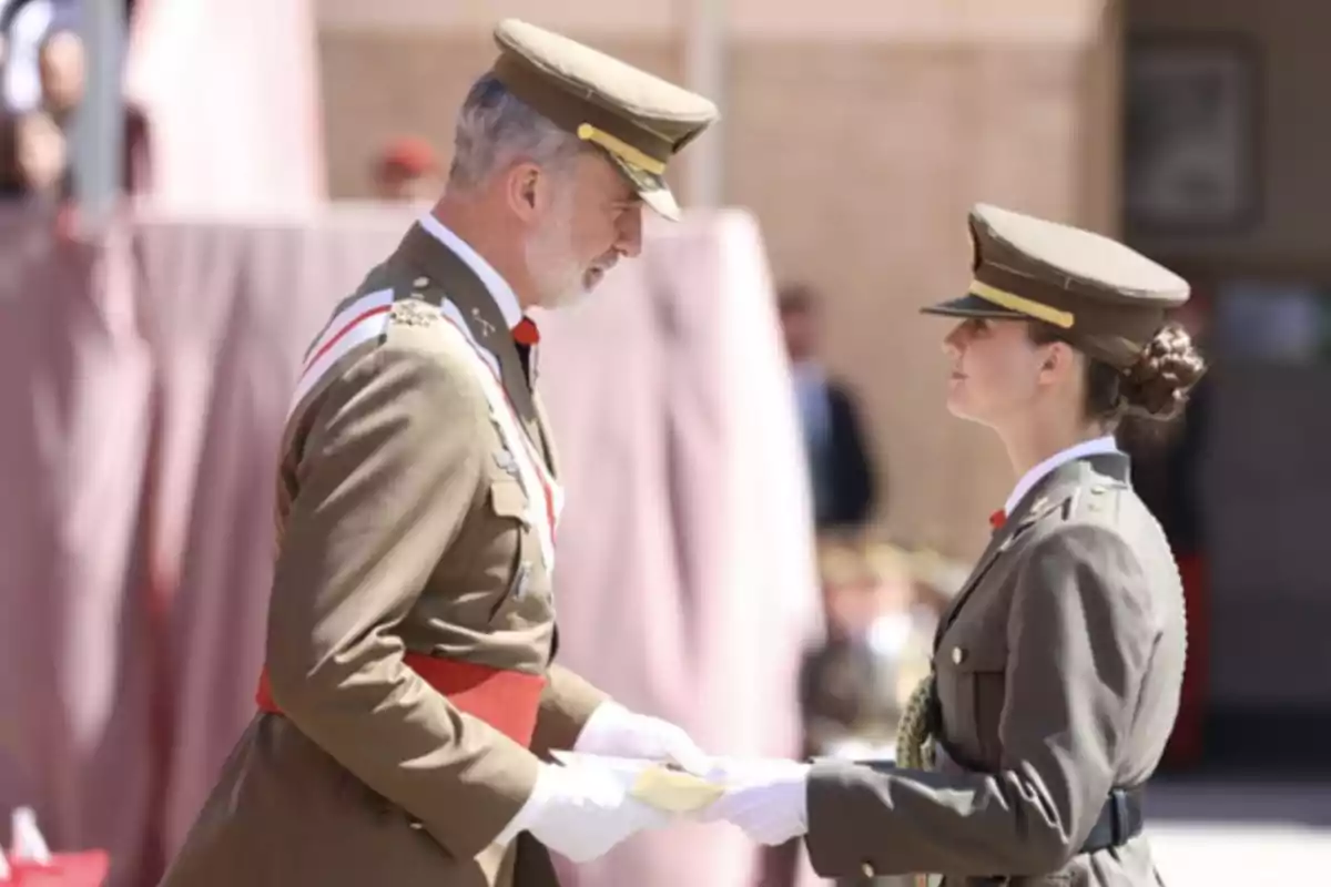 Un oficial militar lliura un document a una oficial en una cerimònia formal.