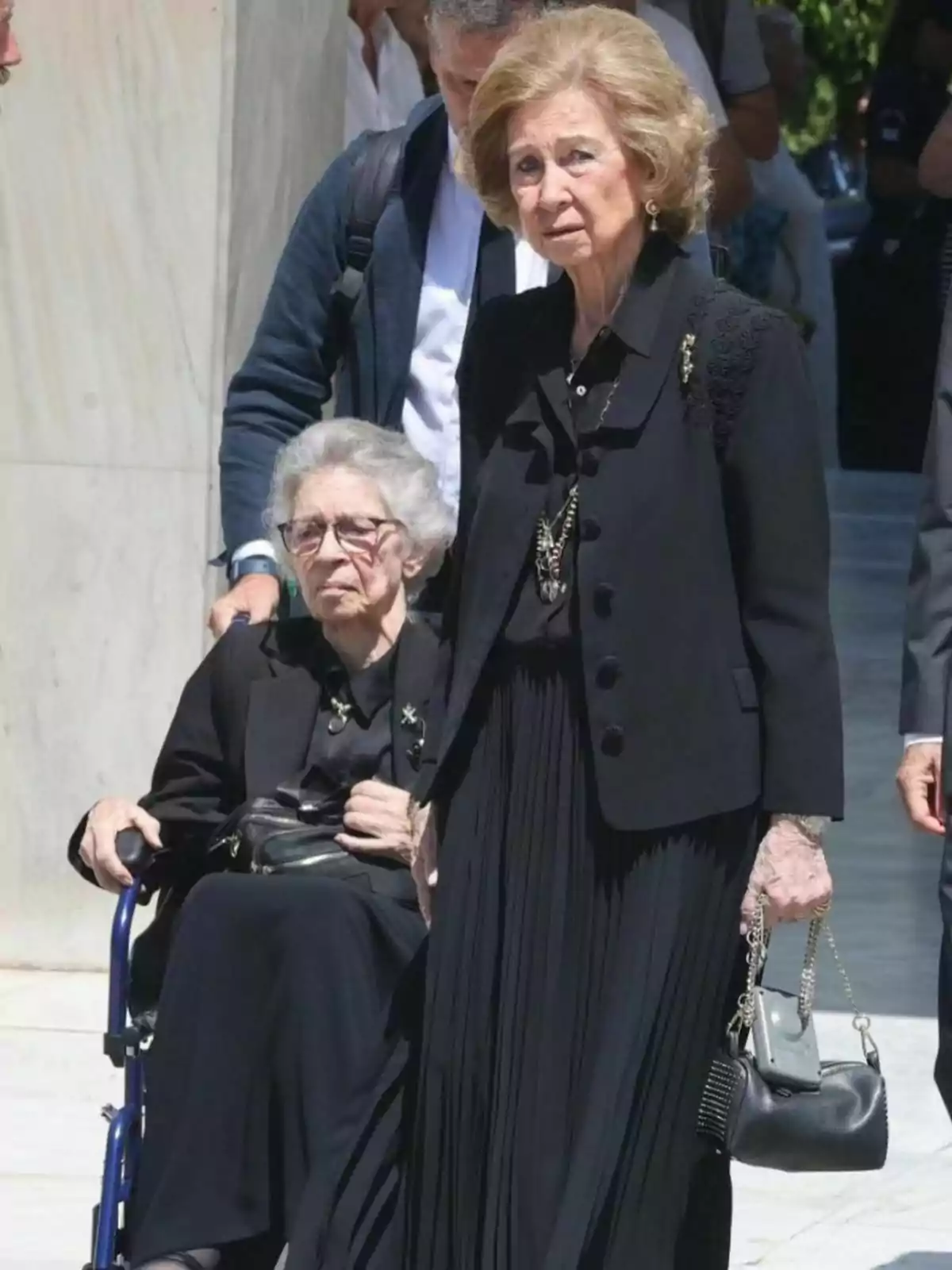 Irene de Grècia i la reina Sofia vestides de negre, Irene en cadira de rodes i Sofia de peu sostenint una bossa, amb persones al fons. Tweet de l'1 d'agost de 2024 Irene de Grècia i la reina Sofia vestides de negre, Irene en cadira de rodes i Sofia de peu sostenint una bossa, amb persones al fons. Tweet de l'1 d'agost de 2024