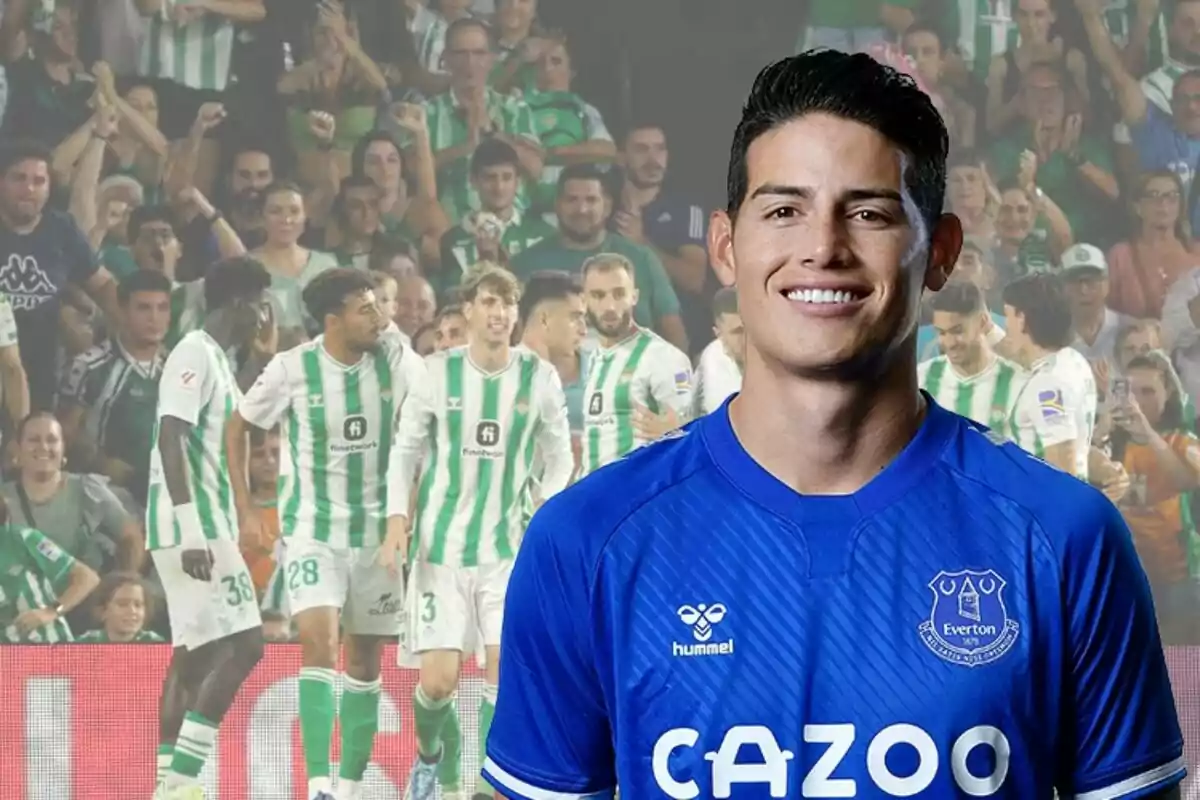 Un jugador de fútbol con la camiseta del Everton sonríe frente a una imagen de jugadores del Real Betis celebrando en el campo con aficionados en el fondo.