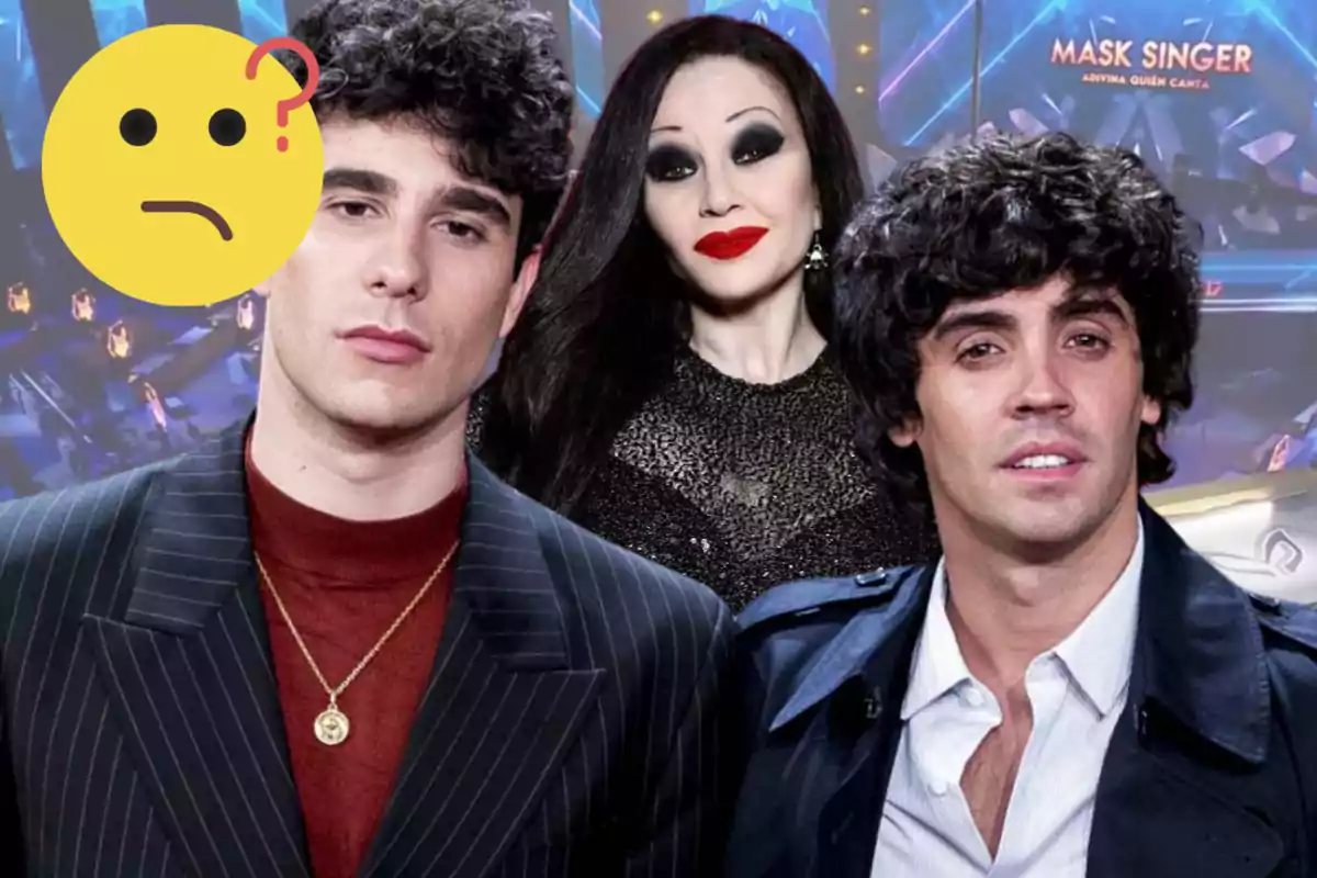 Three people pose in front of a Mask Singer program backdrop while a thinking face emoji partially covers one of them.