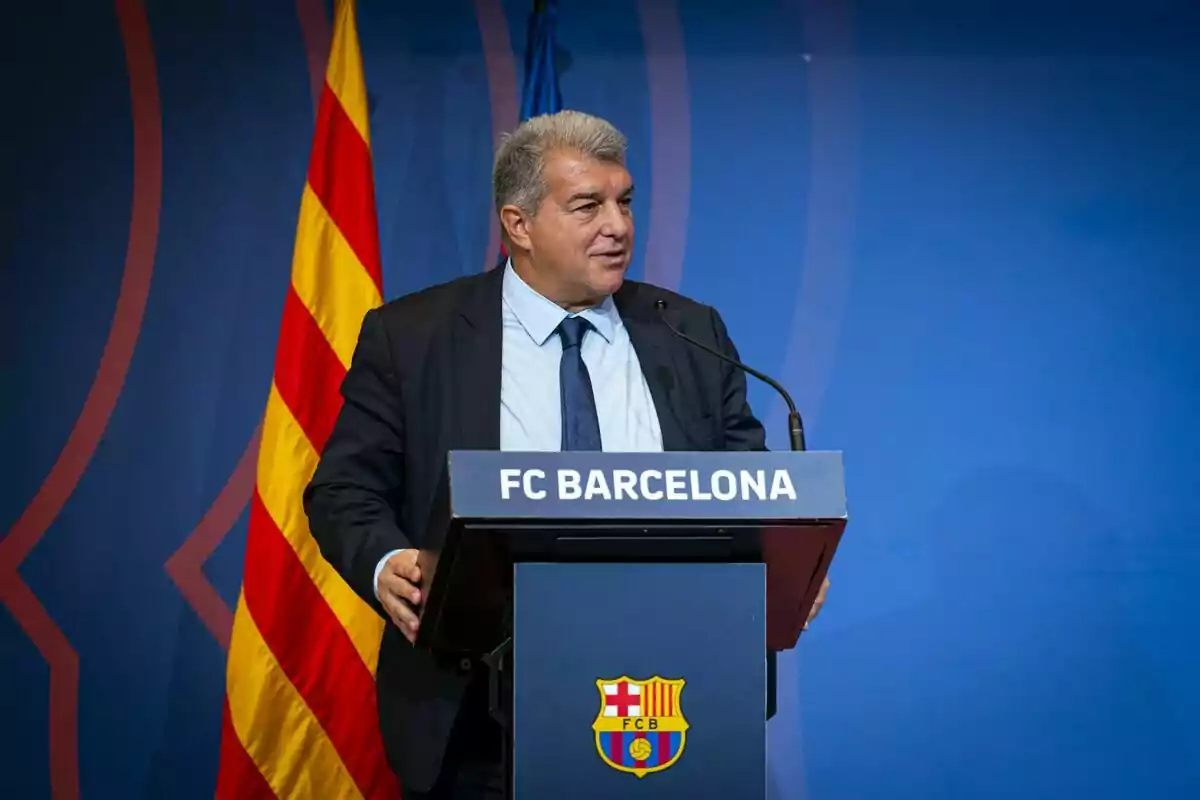 Home parlant en un podi amb el logotip del FC Barcelona i una bandera catalana de fons.