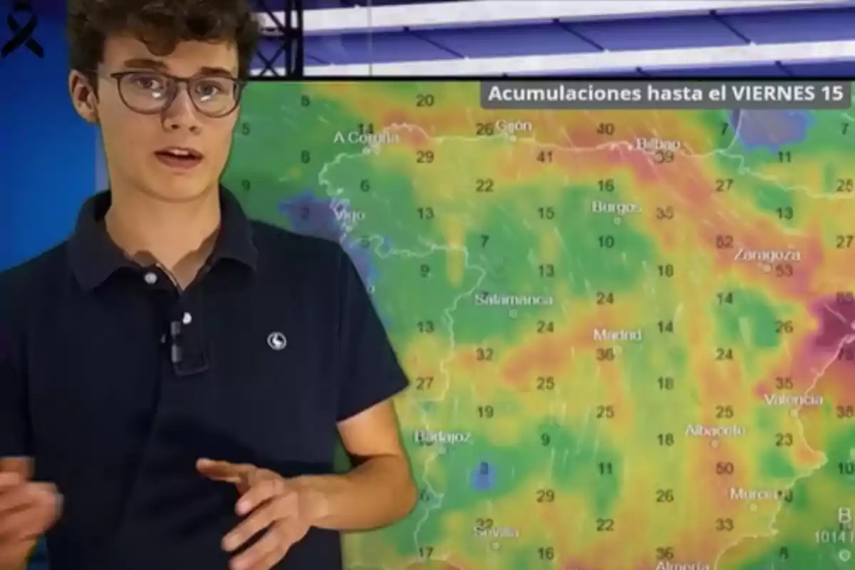 Un joven con gafas y camisa oscura presenta un mapa meteorológico en un estudio de televisión.