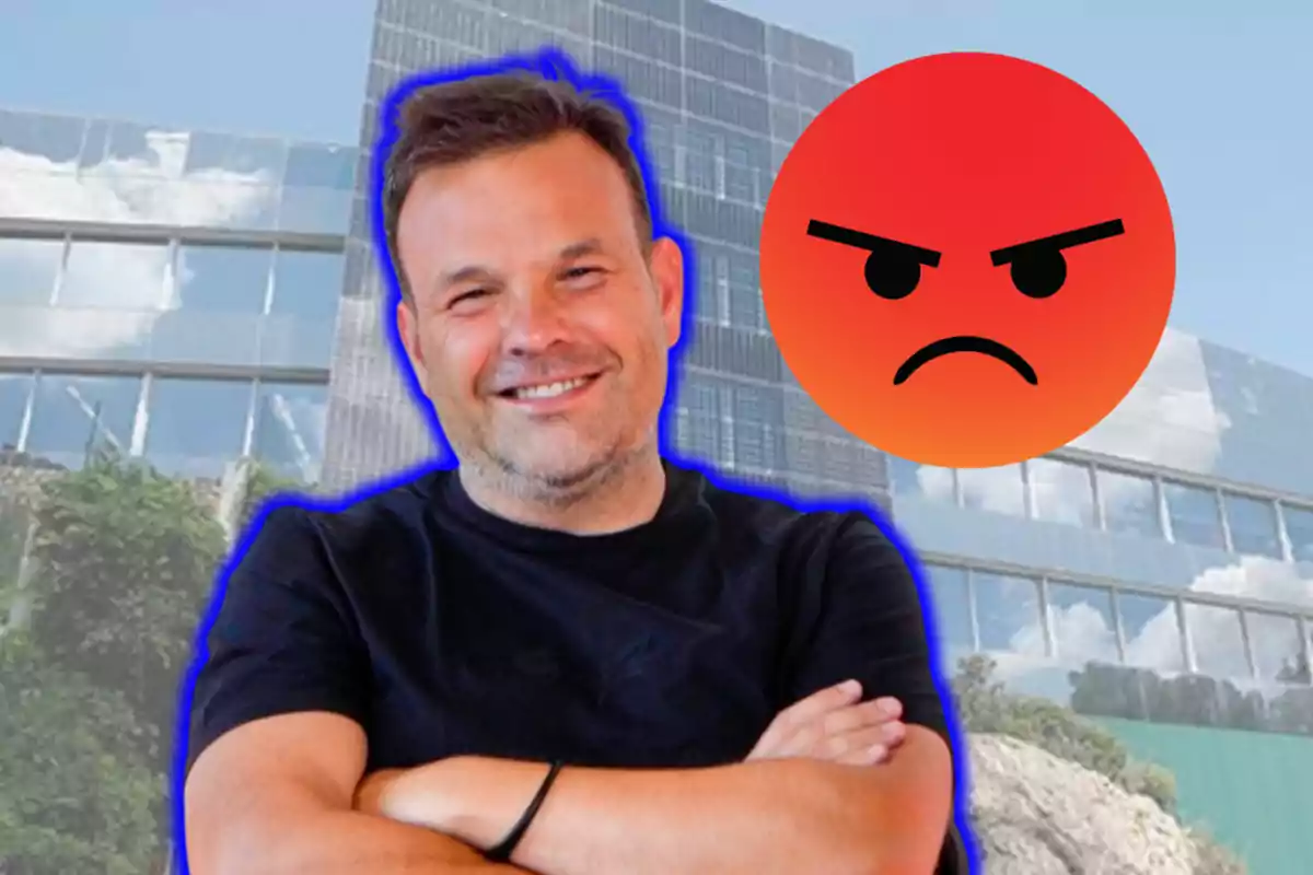 Un home somrient amb els braços creuats davant d'un edifici modern i un emoji d'enfadament flotant al seu costat.