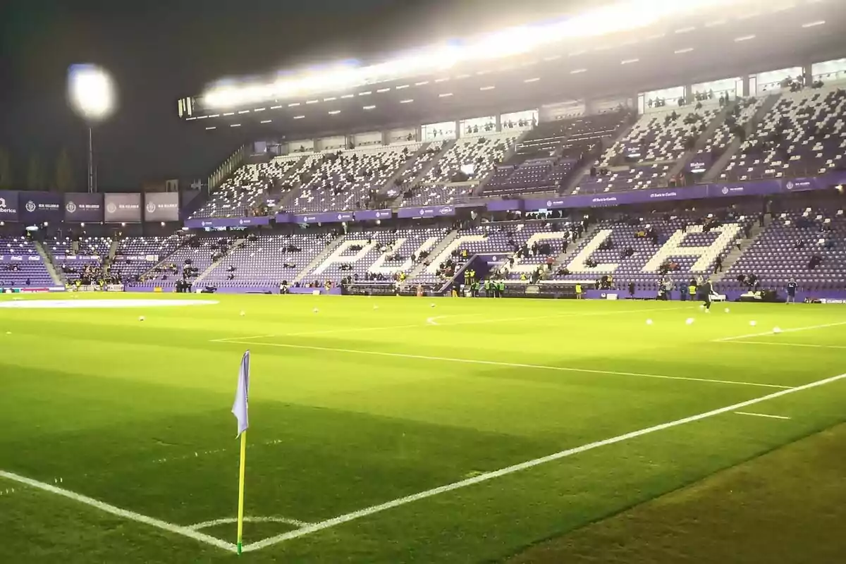 Estadi de futbol il·luminat amb grades parcialment ocupades i el nom Estadi de futbol il·luminat amb grades parcialment ocupades i el nom