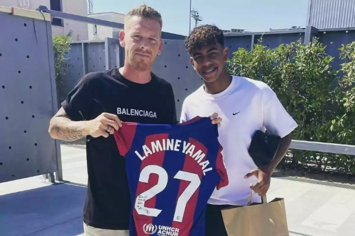 Dos personas posan con una camiseta de fútbol que tiene el nombre "Lamine Yamal" y el número 27.