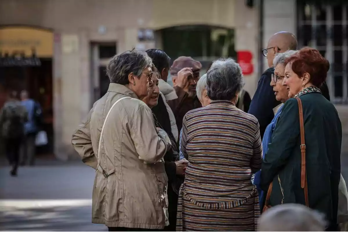 Un grupo de personas mayores conversando en la calle.