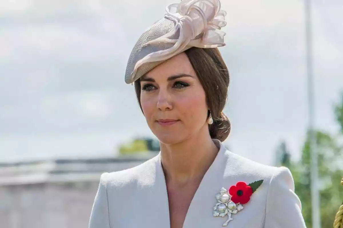 Kate Middleton seria con un tocado beige, el pelo recogido y un pin con una flor Kate Middleton seria con un tocado beige, el pelo recogido y un pin con una flor