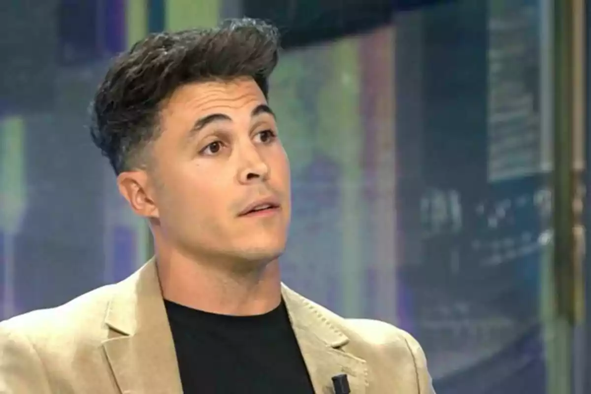 Pla curt de Kiko Jiménez amb jaqueta beix i samarreta negra assegut en un plató de televisió. Pla curt de Kiko Jiménez amb jaqueta beix i samarreta negra assegut en un plató de televisió.