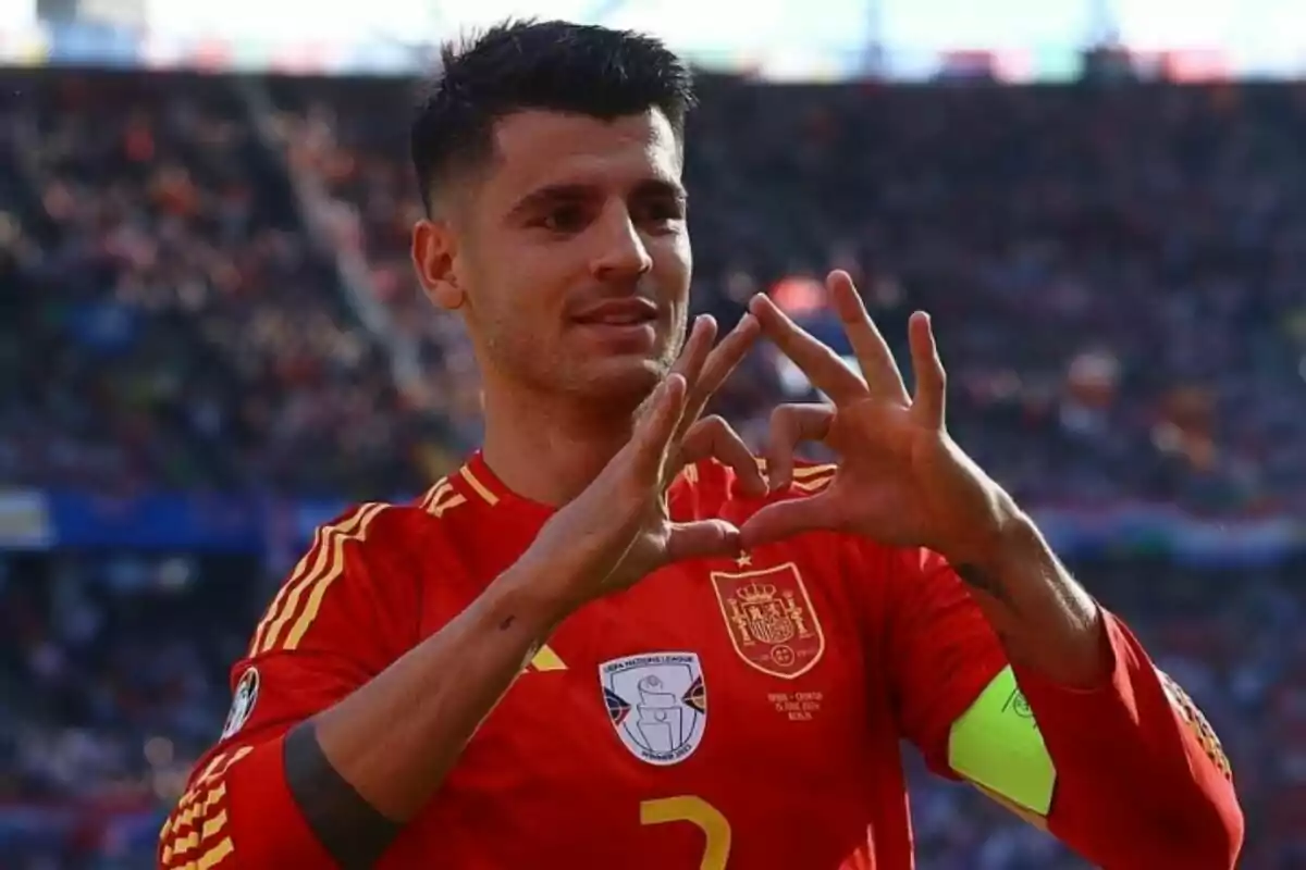 Un jugador de futbol amb la samarreta de la selecció espanyola fa un gest de cor amb les mans a un estadi.