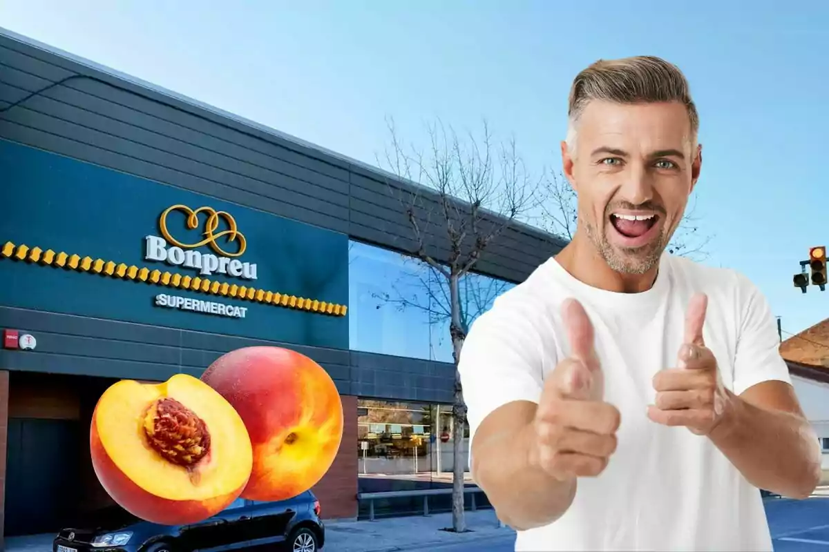 Un hombre sonriente con camiseta blanca apunta con los dedos hacia la cámara, con un supermercado Bonpreu y dos duraznos en el fondo.