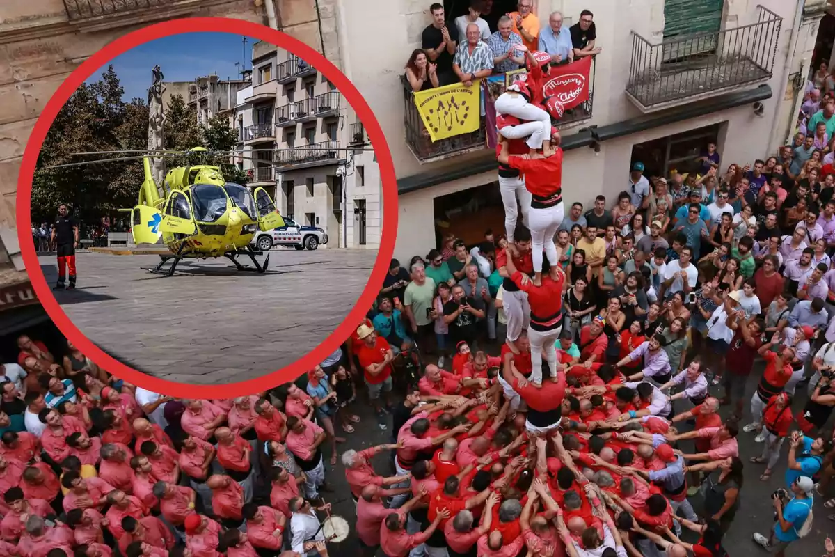 Una multitud observa i participa en la construcció d'un castell humà en un carrer mentre un helicòpter d'emergència està estacionat en una plaça propera.