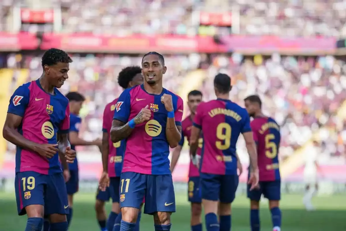 Jugadores de fútbol del FC Barcelona celebrando en el campo con sus uniformes azul y rosa.