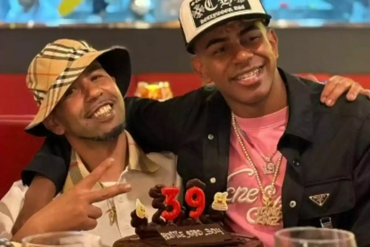 Dos personas sonríen y posan juntas en una celebración de cumpleaños con un pastel que tiene el número 39 en velas.