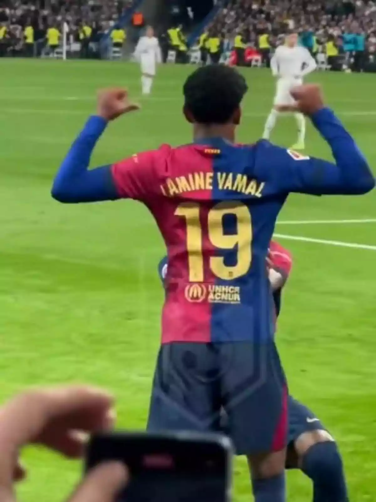 Jugador de fútbol celebrando en el campo con la camiseta del Barcelona número 19 mientras el público observa.