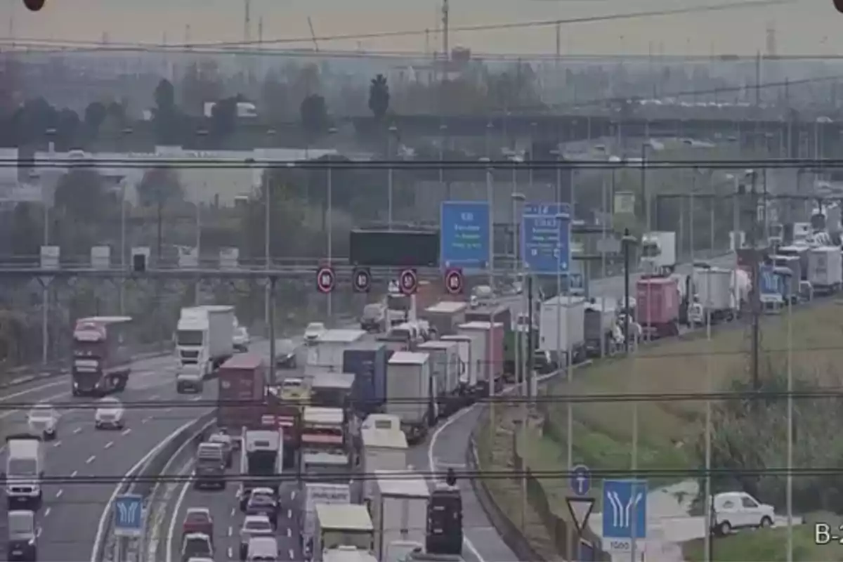 Trànsit dens en una autopista amb nombrosos camions i vehicles en tots dos sentits.